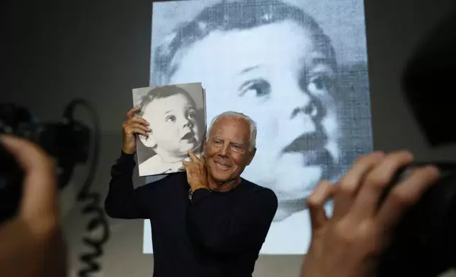 FILE - Italian fashion designer Giorgio Armani poses for photographers holding a copy of the book, 'Giorgio Armani' written by journalist Suzy Menkes, presented at the end his women's Spring-Summer 2016 collection, during fashion week in Milan, Italy, Sept. 28, 2015. (AP Photo/Luca Bruno, File)