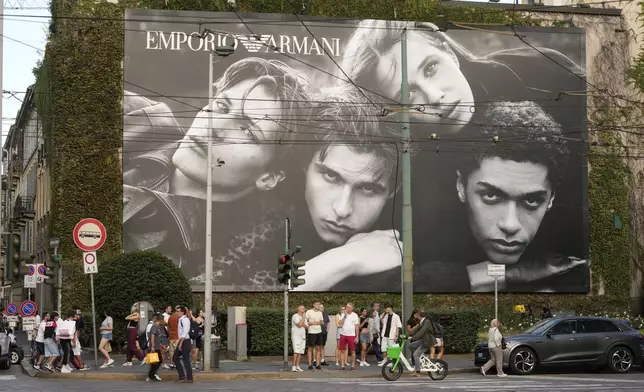 People walk by an advertising for Emporio Armani, the fashion house of designer Giorgio Armani, who died in Milan, Thursday, Sept. 4, 2025. (AP Photo/Luca Bruno)