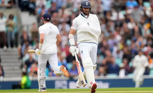 FILE - England's Chris Woakes, right, runs between the wickets with his arm in a sling after a shoulder injury earlier in the match on day five of the fifth cricket test match between England and India at The Kia Oval in London, Monday, Aug. 4, 2025. (AP Photo/Kirsty Wigglesworth, File)