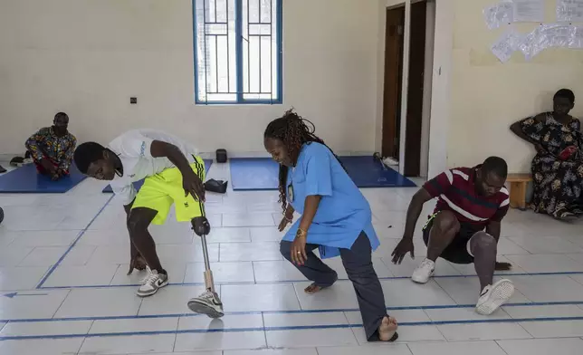 Physiotherapist Gisèle Kantu, center, works with amputees wounded by fighting in the region, at an orthopedic center run by the Catholic church and supported by Red Cross in Goma, eastern Congo, Friday, Aug. 29, 2025. (AP Photo/Moses Sawasawa)
