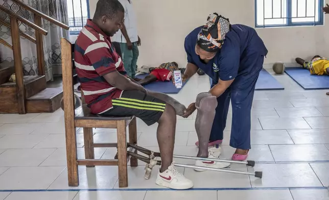 Jerome Jean-Claude Amani, one of many wounded by fighting in the region, receives his prothetic leg from Julienne Paypay, an amputee herself since the age of 6, at an orthopedic center run by the Catholic church and supported by Red Cross in Goma, eastern Congo, Friday, Aug. 29, 2025. (AP Photo/Moses Sawasawa)