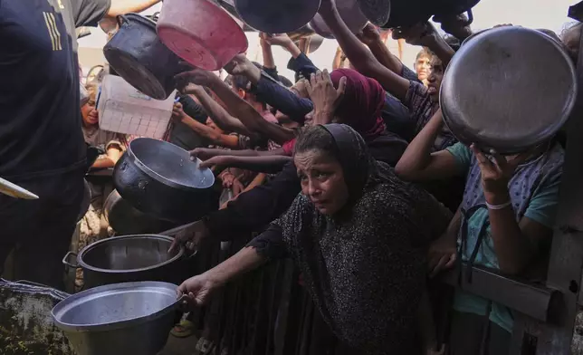 FILE - Palestinians struggle to get donated food at a community kitchen in Khan Younis, southern Gaza Strip, Friday, Sept. 19, 2025. (AP Photo/Jehad Alshrafi, File)