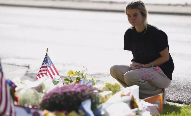 Meagan Bradley kneels at a memorial is set up for Charlie Kirk at Utah Valley University in Orem, Utah, Friday, Sept. 12, 2025. (AP Photo/Lindsey Wasson)