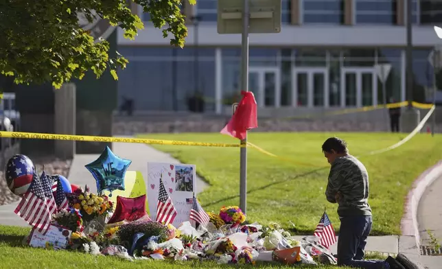 Wendy Lucas, a Utah Valley University student, kneels at a memorial set up for Charlie Kirk at Utah Valley University in Orem, Utah, Friday, Sept. 12, 2025. (AP Photo/Lindsey Wasson)