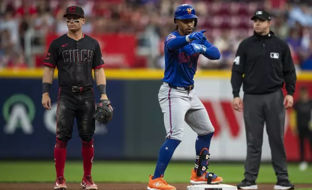 New York Mets Francisco Lindor, center, points at the bench after making it to second base in the third inning of a baseball game against the Cincinnati Reds, Friday, Sept. 5, 2025, in Cincinnati. (AP Photo/Michael Swensen)