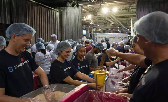 Volunteers work during the "NYC Meal Pack For 9/11 Day" at the Intrepid Sea, Air &amp; Space Museum, Wednesday, Sep. 10, 2025, in New York. (AP Photo/Yuki Iwamura)