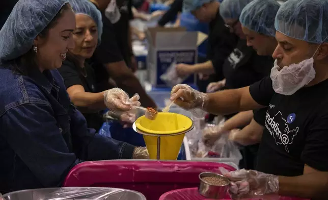 Volunteers work during the "NYC Meal Pack For 9/11 Day" at the Intrepid Sea, Air &amp; Space Museum, Wednesday, Sep. 10, 2025, in New York. (AP Photo/Yuki Iwamura)