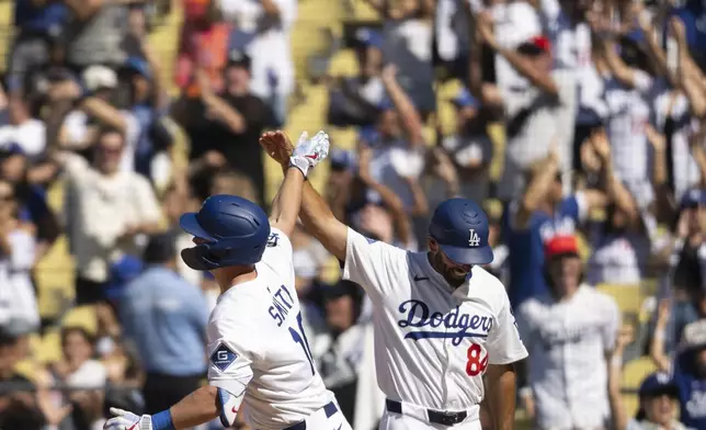 Los Angeles Dodgers' Will Smith, left, celebrates after his walkoff solo home run with first base coach Chris Woodward, right, during the ninth inning of a baseball game against the Arizona Diamondbacks in Los Angeles, Sunday, Aug. 31, 2025. (AP Photo/Kyusung Gong)