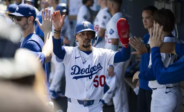 Los Angeles Dodgers' Mookie Betts is greeted in the dugout after scoring on an RBI groundout by Andy Pages during the first inning of a baseball game against the Arizona Diamondbacks in Los Angeles, Sunday, Aug. 31, 2025. (AP Photo/Kyusung Gong)
