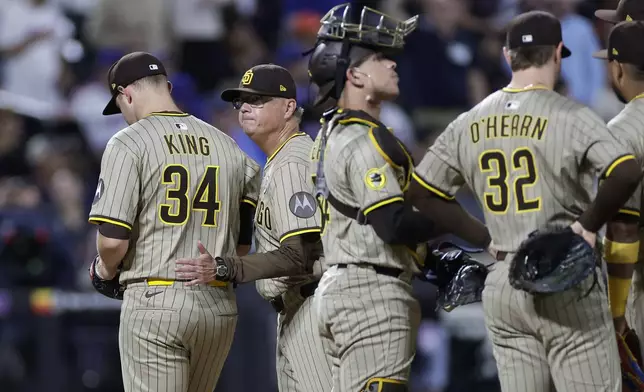 San Diego Padres manager Mike Shildt, second left, pats Michael King (34) on the back as he walks off the mound during the fourth inning of a baseball game against the New York Mets, Tuesday, Sept. 16, 2025, in New York. (AP Photo/Adam Hunger)