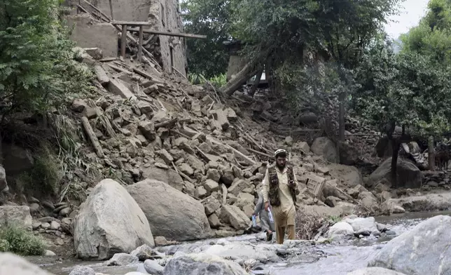 A man and a boy cross a stream of water next to a house destroyed by an earthquake that killed many people and destroyed villages in eastern Afghanistan, in Mazar Dara, Kunar province, Afghanistan, Monday, Sept. 1, 2025. (AP Photo/Wahidullah Kakar)