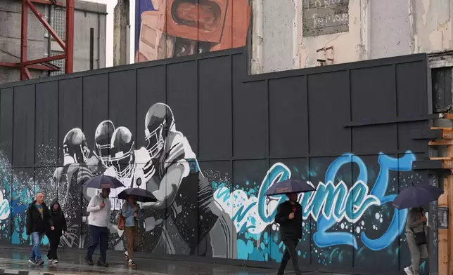 People walk past a temporary NFL football mural ahead of the NFL football match between Minnesota Vikings and Pittsburgh Steelers in Dublin, Saturday, Sept. 27, 2025.(AP Photo/Frank Augstein)