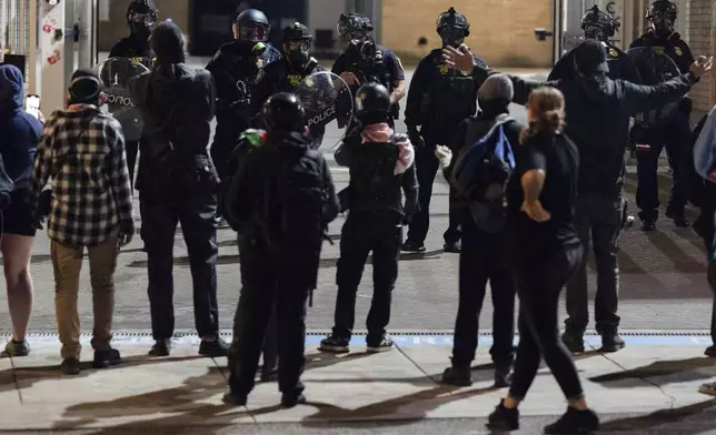 Protesters yell at officers as they walk back to the gates after they created a path for vehicles to exit the U.S. Immigration and Customs Enforcement building in Portland, Ore., on Wednesday, Sept. 10, 2025. (AP Photo/Jenny Kane)