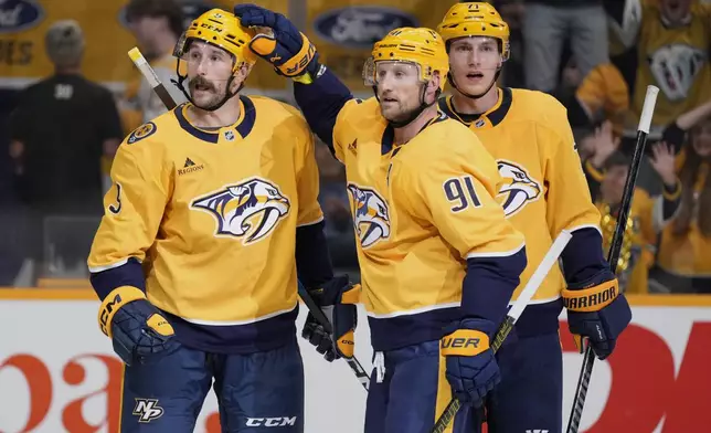Nashville Predators left wing Filip Forsberg (9) is congratulated after his goal by center Steven Stamkos (91) and right wing Matthew Wood (71) during the second period of an NHL preseason hockey game against the Florida Panthers, Sunday, Sept. 21, 2025, in Nashville, Tenn. (AP Photo/George Walker IV)