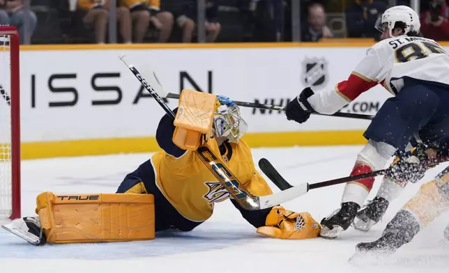 Nashville Predators goaltender Juuse Saros, left, blocks a shot on goal by Florida Panthers left wing Hunter St. Martin, right, during the first period of an NHL preseason hockey game Sunday, Sept. 21, 2025, in Nashville, Tenn. (AP Photo/George Walker IV)