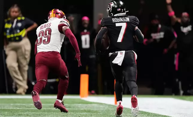Atlanta Falcons running back Bijan Robinson (7) runs the ball past Washington Commanders safety Jeremy Reaves (39) during the second half of an NFL football game, Sunday, Sept. 28, 2025, in Atlanta. (AP Photo/Brynn Anderson)