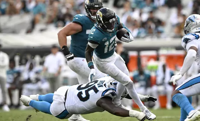 Jacksonville Jaguars wide receiver Travis Hunter (12) runs with the ball against Carolina Panthers defensive end Derrick Brown (95) during the second half of an NFL football game, Sunday, Sept. 7, 2025, in Jacksonville, Fla. (AP Photo/Phelan M. Ebenhack)