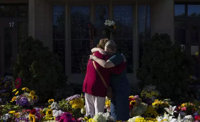 Women embrace at the memorial outside the Annunciation Catholic Church following Wednesday's shooting at the school, Sunday, Aug. 31, 2025, in Minneapolis. (AP Photo/Ellen Schmidt)