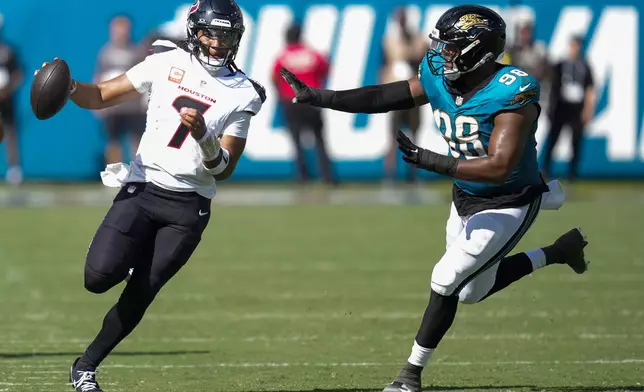 Houston Texans quarterback CJ. Stroud (7) runs the ball as Jacksonville Jaguars defensive end Dawuane Smoot (98) defends during the second half of an NFL football game Sunday, Sept. 21, 2025, in Jacksonville, Fla. (AP Photo/John Raoux)