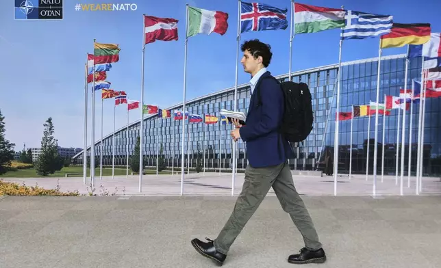 A man walks by a mural with flags of NATO member countries at NATO headquarters in Brussels, Tuesday, Sept. 23, 2025. (AP Photo/Virginia Mayo)