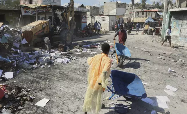 Youths use wheelbarrows to carry debris out of their homes, which were damaged by gang violence, in the Solino neighborhood of Port-au-Prince, Haiti, Wednesday, Sept. 10, 2025. (AP Photo/Odelyn Joseph)