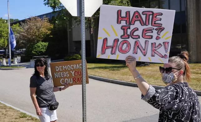 Protesters picket outside the U.S. Immigration and Customs Enforcement regional field office, at rear, Thursday, Sept. 11, 2025, in Burlington, Mass. (AP Photo/Charles Krupa)