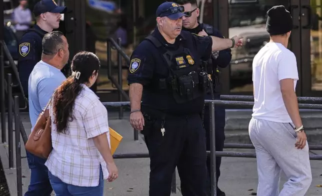 A Department of Homeland Security police officer directs visitors towards the front door of the U.S. Immigration and Customs Enforcement regional field office, Tuesday, Sept. 16, 2025, in Burlington, Mass. (AP Photo/Charles Krupa)