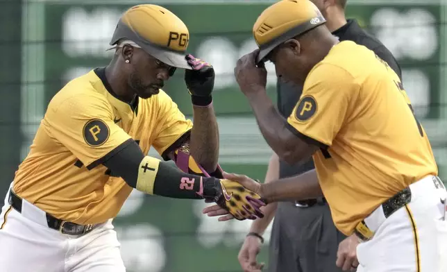 Pittsburgh Pirates' Andrew McCutchen, left, celebrates with first base coach Tarrik Brock, after hitting a single off Athletics pitcher Luis Severino during the first inning of a baseball game in Pittsburgh, Friday, Sept. 19, 2025. (AP Photo/Gene J. Puskar)