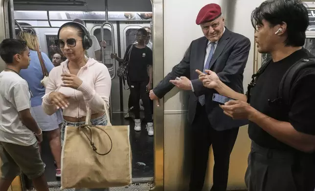 New York Mayor candidate Curtis Sliwa holds a subway door for a passenger as he campaigns in the New York City subway system, Monday, Aug. 18, 2025. (AP Photo/Richard Drew)