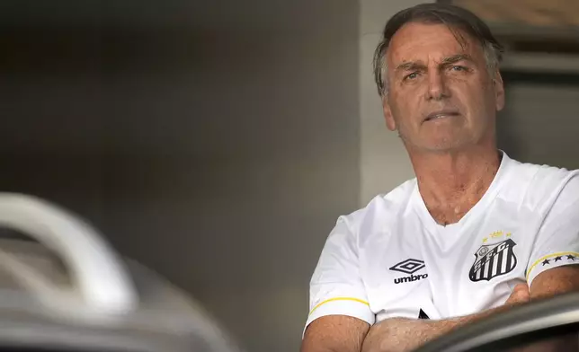Brazil's former President Jair Bolsonaro stands at the entrance to his home where he is under house arrest in Brasilia, Brazil, Friday, Aug. 29, 2025. (AP Photo/Eraldo Peres)