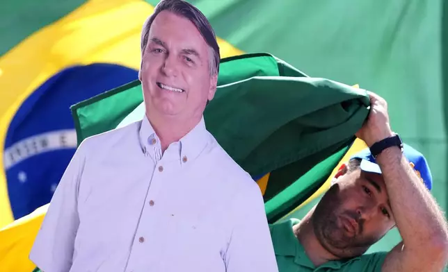 A supporter of former President Jair Bolsonaro prepares a doll with his image, during a protest against his trial, in front of the condominium where he is under house arrest, in Brasilia, Brazil, Sunday, Aug. 31, 2025. (AP Photo/Eraldo Peres)