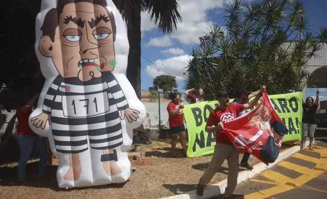 Demonstrators hold up an inflatable doll depicting Brazil's former President Jair Bolsonaro wearing prisoner garb, during a protest demanding his imprisonment outside the condominium where he is under house arrest, in Brasilia, Brazil, Tuesday, Sept. 2, 2025. (AP Photo/Luis Nova)