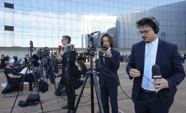 Journalists work outside the Supreme Court prior to the verdict and sentencing phase of a trial for those charged in an alleged coup plot to keep Brazil's former President Jair Bolsonaro in office after his 2022 election defeat, in Brasilia, Brazil, Tuesday, Sept. 2, 2025. (AP Photo/Eraldo Peres)