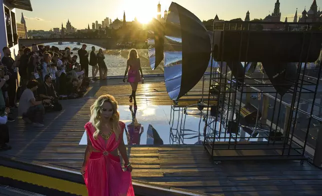 Model wear a creation by Russian designer Julia Dalakian on the Floating Bridge during sunset at Moscow Fashion Week at Zaryadye park in Moscow, Monday, Sept. 1, 2025, with the Kremlin in the background. (AP Photo/Alexander Zemlianichenko)