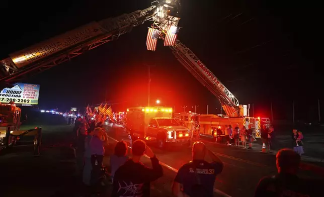 People salute as an ambulance drives past during a procession Wednesday, Sept. 17, 2025, in Spring Grove, Pa., after multiple police officers were shot and killed. (AP Photo/Matt Slocum)
