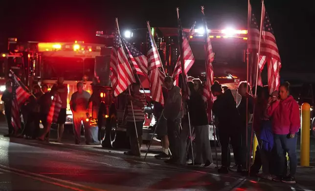 People hold American flags before a procession Wednesday, Sept. 17, 2025, in Spring Grove, Pa., after multiple police officers were shot and killed. (AP Photo/Matt Slocum)