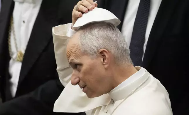 Pope Leo XIV tries a skull cap which was hand to him by faithful during the weekly general audience at the Vatican, Wednesday, Aug. 27, 2025. (AP Photo/Gregorio Borgia)