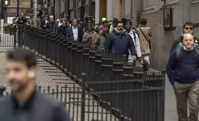 FILE - Commuters walk past the New York Stock Exchange, April 8, 2025, in New York. (AP Photo/Yuki Iwamura, File)