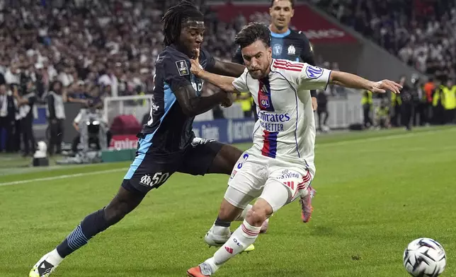 Lyon's Nicolas Tagliafico, right, challenges for the ball with Marseille's Darryl Bakola, left, during the French League One soccer match between Lyon and Marseille in Decines, France, Sunday, Aug. 31, 2025. (AP Photo/Laurent Cipriani)