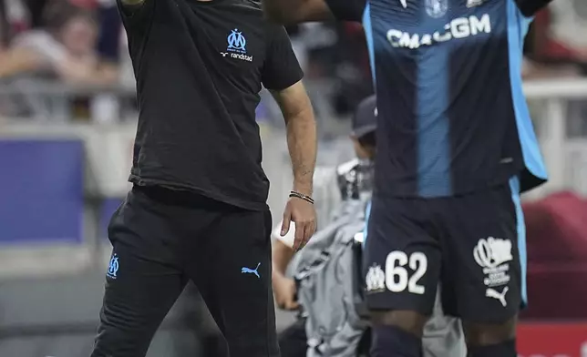 Marseille's head coach Roberto De Zerbi, left, gestures during the French League One soccer match between Lyon and Marseille, in Decines, outside Lyon, France, Sunday, Aug. 31, 2025. (AP Photo/Laurent Cipriani)