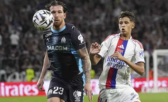 Marseille's Pierre-Emile Hojbjerg, left, challenges for the ball with Lyon's Khalis Merah during the French League One soccer match between Lyon and Marseille, in Decines, outside Lyon, France, Sunday, Aug. 31, 2025. (AP Photo/Laurent Cipriani)