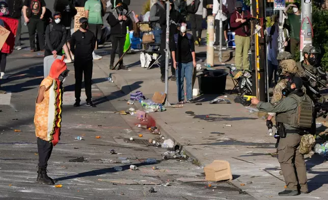 FILE - A law enforcement officer points a taser at a person wearing a hot dog costume during a protest Saturday, June 14, 2025, in Portland, Ore. (AP Photo/Jenny Kane, File)