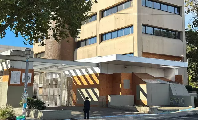 A person stands outside a U.S. Immigration and Customs Enforcement facility on Saturday, Sept. 27, 2025 in Portland, Ore. (AP Photo/Gillian Flaccus)