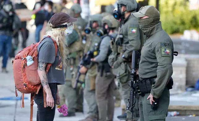FILE - A woman stands off with a law enforcement officer wearing a Houston Field Office Special Response Team patch outside the U.S. Immigration and Customs (ICE) building during a protest Saturday, June 14, 2025, in Portland, Ore. (AP Photo/Jenny Kane, File)