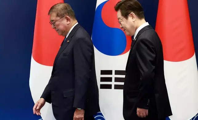 South Korean President Lee Jae Myung, right, walks with Japanese Prime Minister Shigeru Ishiba on their way to hold a meeting in Busan, South Korea, Tuesday, Sept. 30, 2025. (Yonhap via AP)