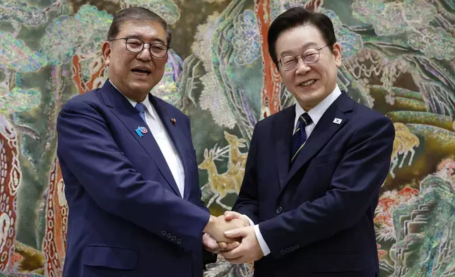South Korean President Lee Jae Myung, right, shakes hands with Japanese Prime Minister Shigeru Ishiba, left, during a meeting in Busan, South Korea, Tuesday, Sept. 30, 2025. (Yonhap via AP)