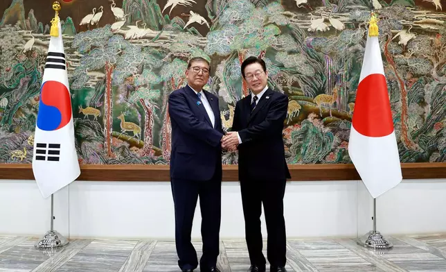 South Korean President Lee Jae Myung, right, shakes hands with Japanese Prime Minister Shigeru Ishiba during a meeting in Busan, South Korea, Tuesday, Sept. 30, 2025. (Yonhap via AP)