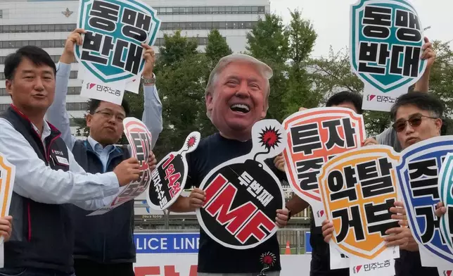 A member of the Korean Confederation of Trade Unions, wearing masks of U.S. President Donald Trump, protests against Trump's tariff policy on South Korea near the presidential office in Seoul, Tuesday, Sept. 30, 2025. The signs read "Stop investment and Oppose alliance?" (AP Photo/Ahn Young-joon)