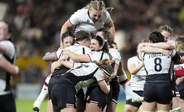 Canada's Courtney O'Donnell, top, and teammates celebrate after winning the Women's Rugby World Cup 2025 semifinal match between Canada and New Zealand at Ashton Gate, Bristol, England, Friday Sept. 19, 2025. (Andrew Matthews/PA via AP)