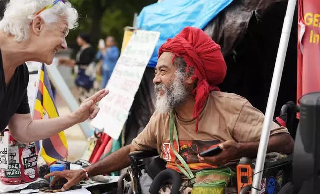 Philipos Melaku-Bello smiles as he speaks to a passerby at the White House Peace Vigil in Lafayatte Park across the street from the White House in Washington, Friday, Sept. 5, 2025. (AP Photo/Pablo Martinez Monsivais)